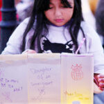 Eight-year-old Zuanny arranges luminaries with messages about her mother, a DACA "Dreamer," herself and her sisters during a vigil at La Colaborativa in Chelsea, Mass., Oct. 10, 2025, for the community affected by raids and detentions by Immigration and Customs Enforcement. (OSV News photo/Brian Snyder, Reuters)